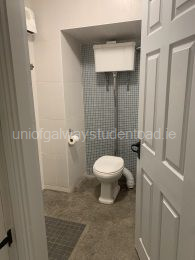 Wet room with electric wall heater, toilet and sink with drawer storage 
