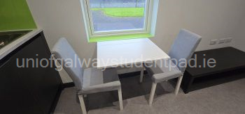 Collapsible dining table with two chairs. Chairs stored in bedroom at desk and behind couch. 