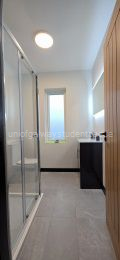 Bathroom with large LED lit mirror, vanity unit, toilet and shower